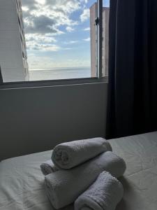 a bed with towels on it with a window at Mar doce lar in São Luís