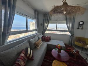 a living room with a couch and large windows at Telemly Douira el ALIA Alger in LʼAgha