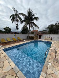 a swimming pool with chairs and a palm tree at Casa com piscina in Bertioga