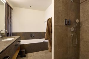 a bathroom with a tub and a sink and a shower at Das Lakeside - Move&Relax in Walchsee +23 photos