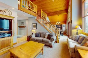 a living room with a couch and a tv and stairs at Coyote Creek Chalet in Big White