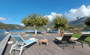 a group of chairs and tables on a wooden deck at Reflets du Lac Annecy, Baie des Voiles - Vue Lac - Terrasse - Plage & Parking Privés in Duingt