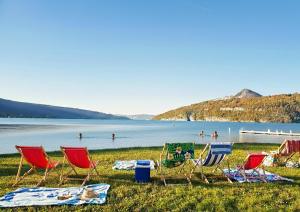 a group of lawn chairs and people on a lake at Reflets du Lac Annecy, Baie des Voiles - Vue Lac - Terrasse - Plage & Parking Privés in Duingt +42 photos