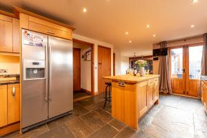 a kitchen with a stainless steel refrigerator and wooden cabinets at Silverwood Stylish House - Pass the Keys in Telford