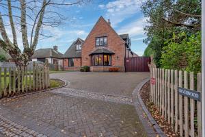 a brick house with a fence and a driveway at Silverwood Stylish House - Pass the Keys in Telford