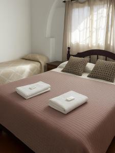 two white towels are sitting on a bed at Petit Hotel Las Marias in La Rioja