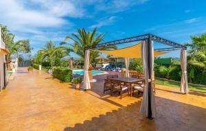 a patio with a table and a canopy next to a pool at Ca Na Pepa in Muro
