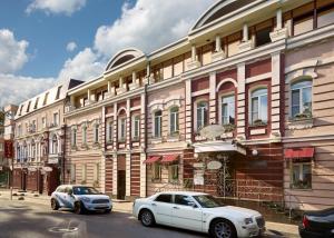 twee auto's geparkeerd voor een gebouw bij Residentsiya (Izvolte) Hotel in Rostov aan de Don