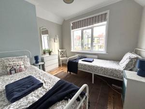 a bedroom with two beds and a window at Downs Gate Cottage in Eastbourne
