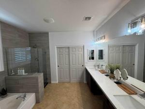 a bathroom with two sinks and a tub and a shower at Homes by Abby LLC in Maricopa