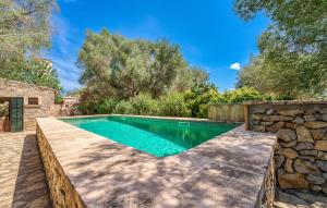 a swimming pool in a yard with a stone wall at Moli Den Guixo in Artá