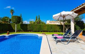 a swimming pool with two chairs and an umbrella at Gatoses in Sa Coma