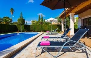 two lounge chairs and an umbrella next to a swimming pool at Gatoses in Sa Coma