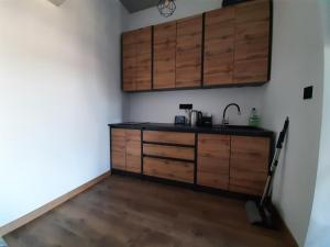 a kitchen with wooden cabinets and a wooden floor at Apartament 12 in Zwardoń