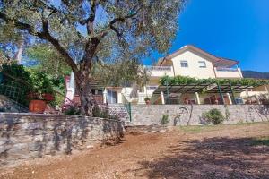 a house behind a stone wall with a tree at Nestor Apartments in Chrysi Ammoudia