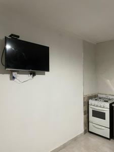 a flat screen tv hanging on a wall next to a stove at Casa de Lore in Necochea +2 photos