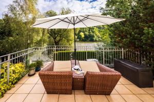 a wicker table with an umbrella on a patio at Elbvilla Pirna mit Sauna und Kamin mit privatem Zugang zur Elbe in Pirna