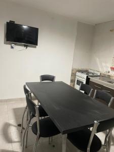 a dining room table with chairs and a tv on the wall at Casa de Lore in Necochea