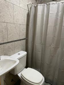 a bathroom with a white toilet and a sink at Casa de Lore in Necochea