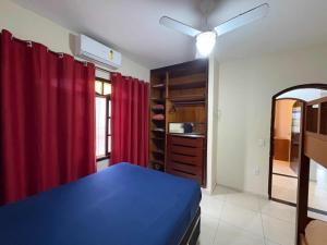 a bedroom with a blue bed and a red curtain at Casa com piscina in Bertioga +80 photos