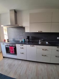 a kitchen with white cabinets and a sink and a stove at Ferienwohnung Elisa in Staig