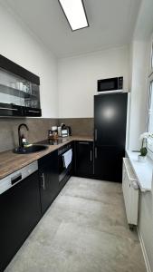 a kitchen with black cabinets and a black refrigerator at Paulus Living in Halle an der Saale