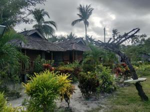 a house with palm trees and plants in front of it at Bamboo Basecamp in El Nido