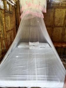 a bed with a mosquito net in a room at Bamboo Basecamp in El Nido