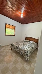a bed in a bedroom with a wooden ceiling at Cantinho da Nara em Ibitipoca in Conceição da Ibitipoca
