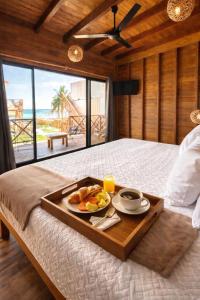 a tray of food on a bed with a view of the ocean at Hotel Solana Bacalar Lakefront in Bacalar