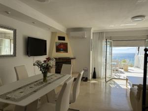 a dining room with a table and chairs and a television at Mediterranean Escape with Panoramic Sea Views in Benalmádena