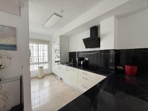 a kitchen with white cabinets and black counter tops at Mediterranean Escape with Panoramic Sea Views in Benalmádena