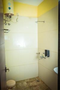 a bathroom with a shower with a toilet and a sink at The Shrine Hotel in Godarpura