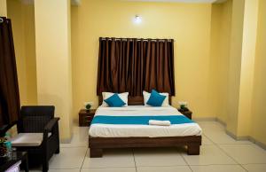 a bedroom with a bed with blue pillows and a window at The Shrine Hotel in Godarpura