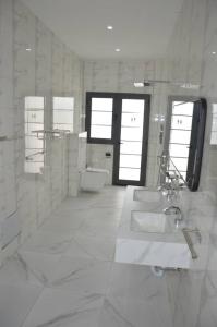 a white bathroom with two sinks and a toilet at Villa Keur Carla in Niangol +5 photos