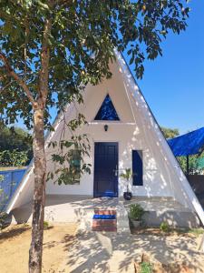 a small white house with a triangular roof at Mung Kham Stays in Jorhat