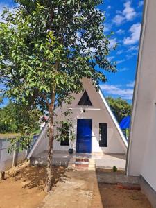 a small white church with a blue door and a tree at Mung Kham Stays in Jorhat