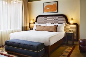 a bedroom with a large bed with a blue ottoman at The Hoxton, Dublin in Dublin