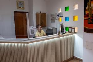 a man is sitting at a counter in a store at Altoparque Hotel Salta in Salta
