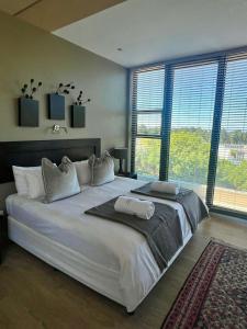 a large white bed in a room with windows at House Vos in Hermanus