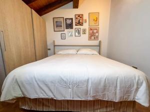 a bedroom with a white bed with pictures on the wall at La Maison Pilly in Sondalo