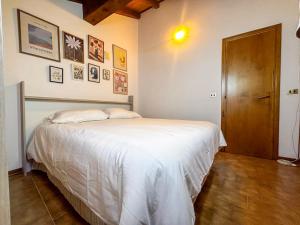 a bedroom with a white bed and a wooden door at La Maison Pilly in Sondalo