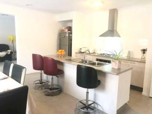 a kitchen with three bar stools and a counter top at Point Cook Homestay House in Point Cook +9 photos