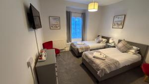 a hotel room with two beds and a tv at Anglebury House in Wareham