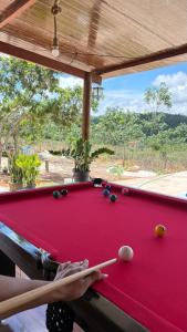 a person playing pool on a red pool table at Refúgio das Araras in Pirenópolis