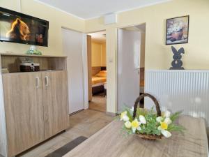 a living room with a television and a basket of flowers at Boglárka Apartmanház in Mezőkövesd