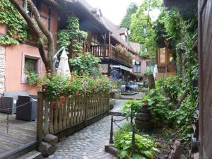 a courtyard of a house with flowers and a fence at Chez Norbert in Bergheim
