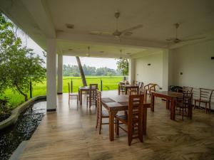 a dining room with tables and chairs and a field at Man Guest Polonnaruwa in Polonnaruwa