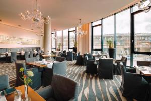 a restaurant with tables and chairs and large windows at MÖVENPICK Hotel Stuttgart Airport in Leinfelden-Echterdingen