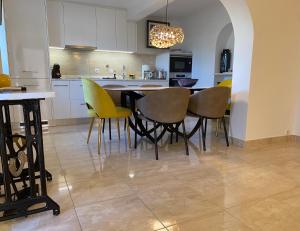 a kitchen with a dining table and yellow chairs at Vila Monte Luz 3 in Ferragudo